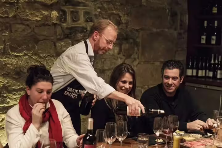 Sommelier pouring red wine for guests during an intimate Paris wine tasting in a stone cellar