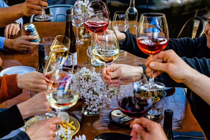 Group toasting with glasses of wine on a Paris gourmet tour, featuring diverse selections of red, white, and rosé wines.