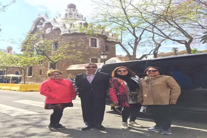Tourists enjoying a visit to Park Güell in Barcelona, with Gaudí's architectural masterpiece in the background.