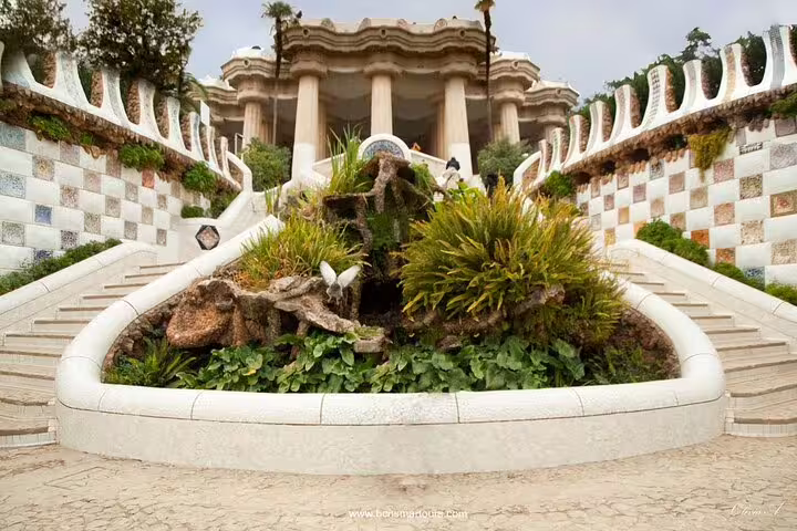 Park Güell grand staircase with mosaic railings and lush greenery, Barcelona