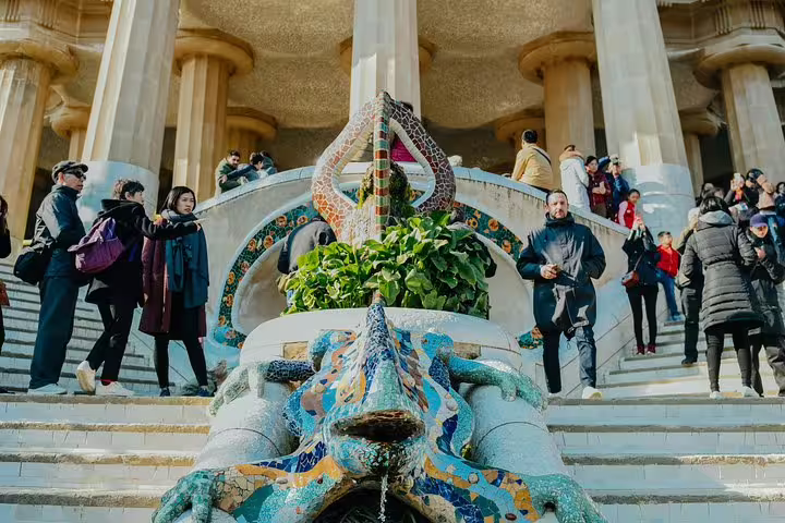 Tourists explore the vibrant mosaic dragon fountain at Park Güell in Barcelona, a highlight of the city's cultural tours.