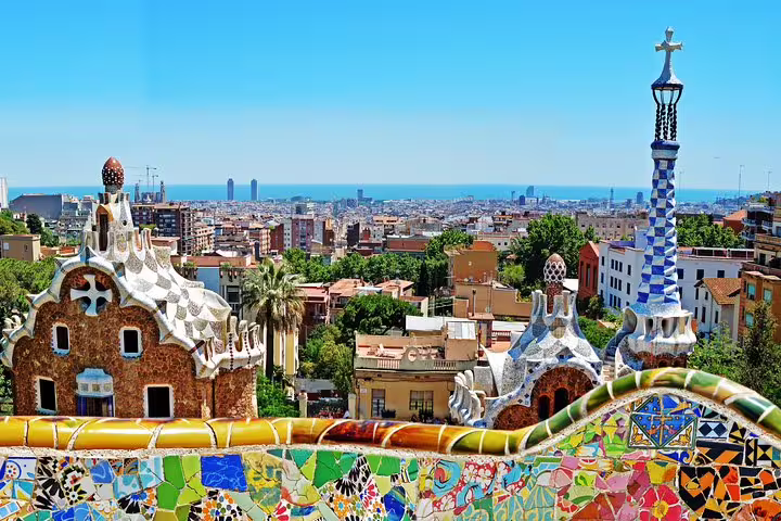 Vibrant mosaic tiles and unique architecture of Park Güell offering panoramic views of Barcelona cityscape.