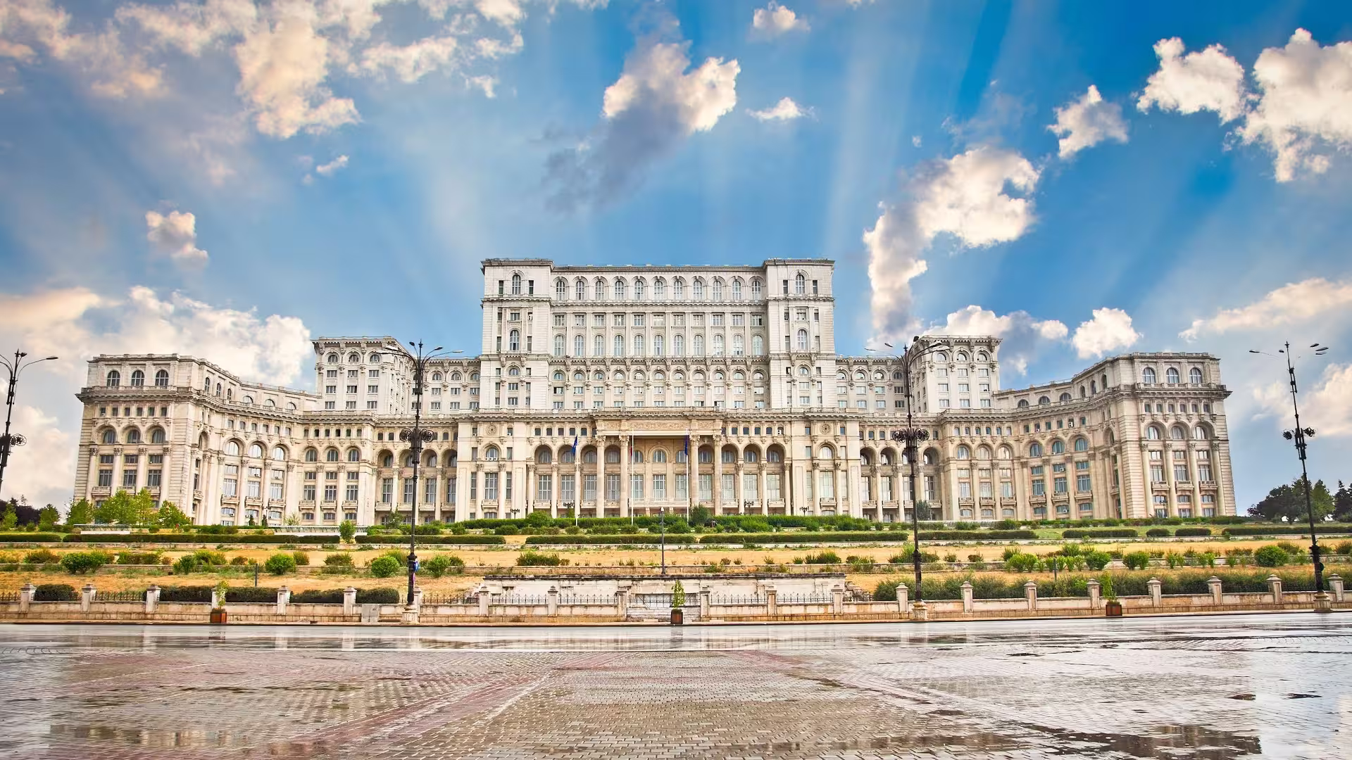 Majestic front view of Parliament Palace in Bucharest under a vibrant blue sky, highlighting its grand architecture.