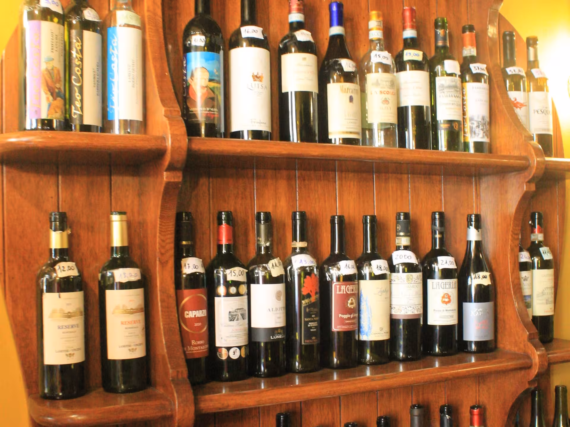 A wooden shelf filled with a diverse selection of Italian wines, showcasing Parma's rich wine culture on a food tour.