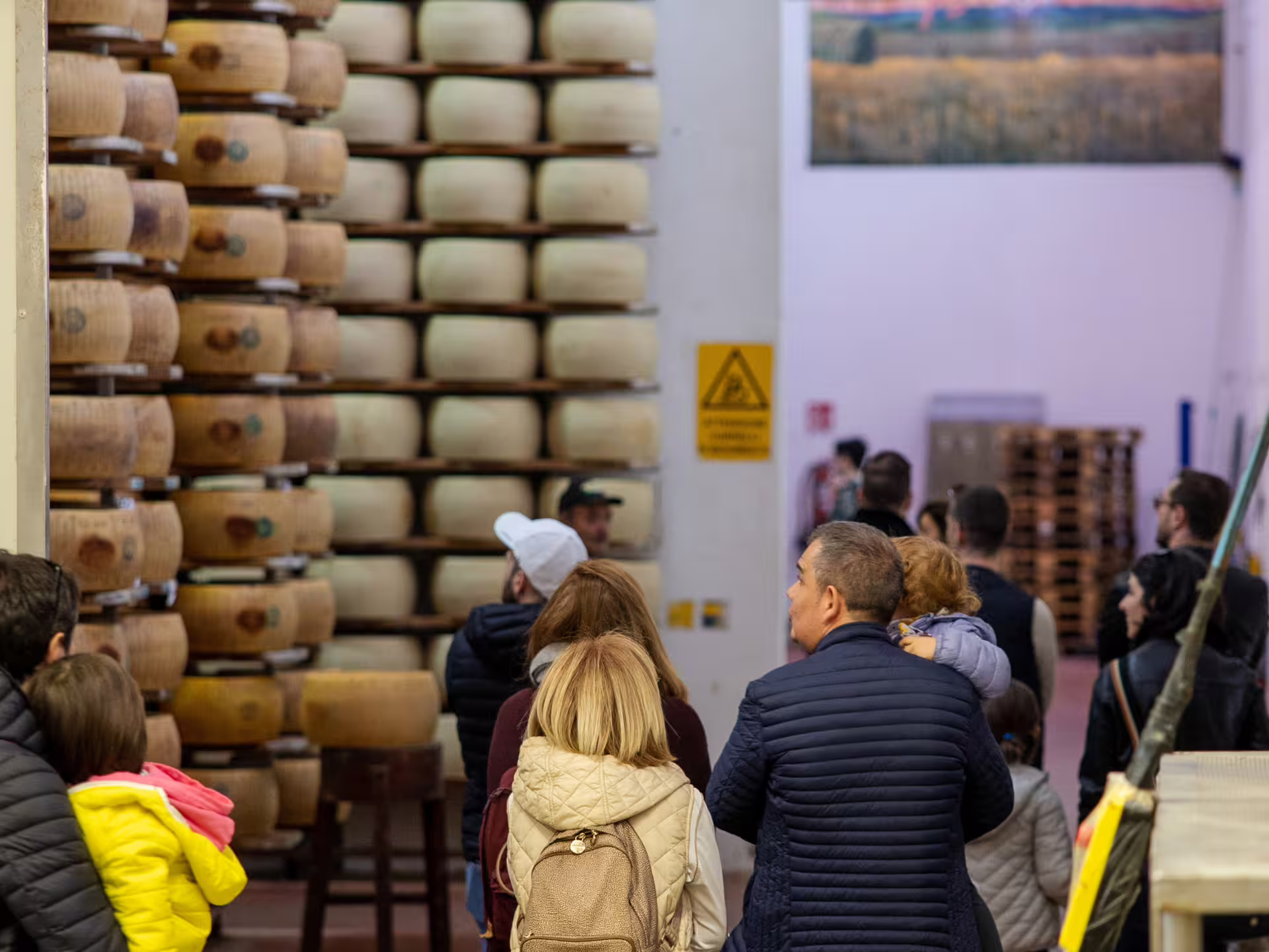 Visitors walk through a Parmigiano Reggiano aging room on a Parmesan cheese factory tour near Modena