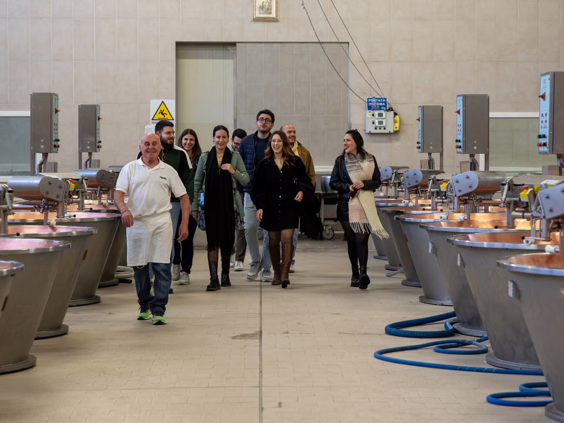 Visitors follow guide through Parmigiano Reggiano dairy room with copper vats on Modena tasting tour