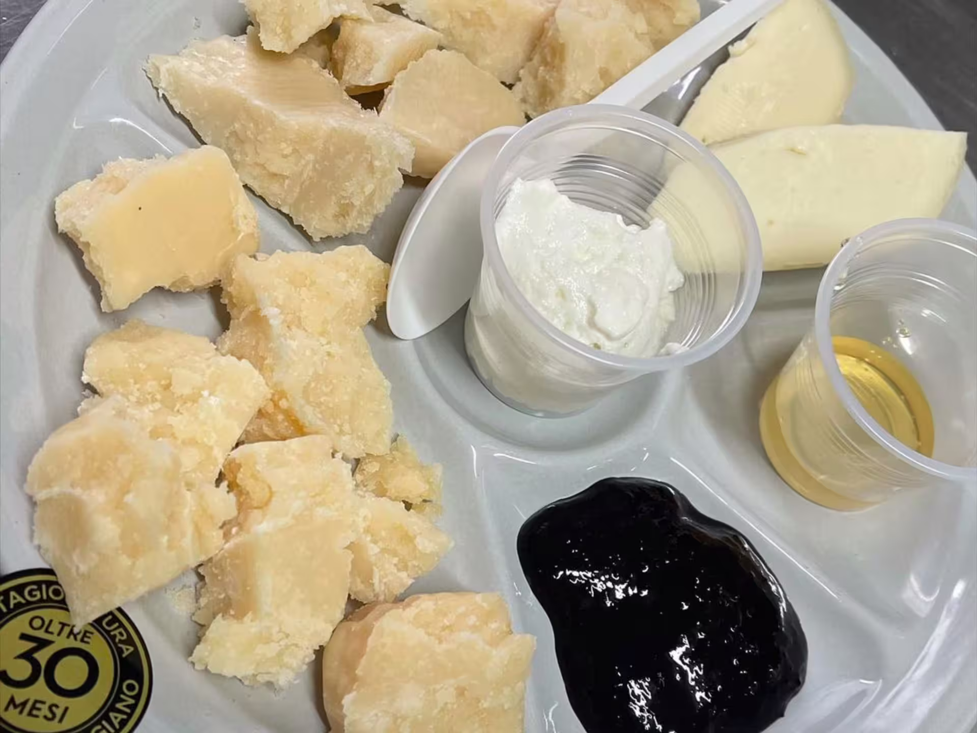Parmigiano Reggiano tasting plate with aged Parmesan chunks, ricotta, balsamic and wine on Modena tour