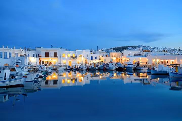 Paros Naoussa harbor at dusk with boats and waterfront lights on a 7-day Mykonos Paros Santorini tour