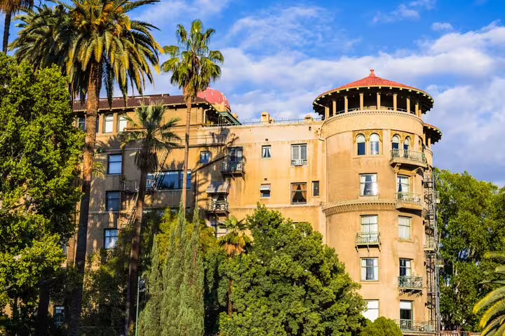 Historic Pasadena building with round tower and red dome surrounded by palm trees