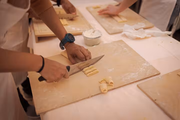 Hands-on pasta cutting during a cooking class in Rome's Piazza Navona, showcasing Italian culinary skills.