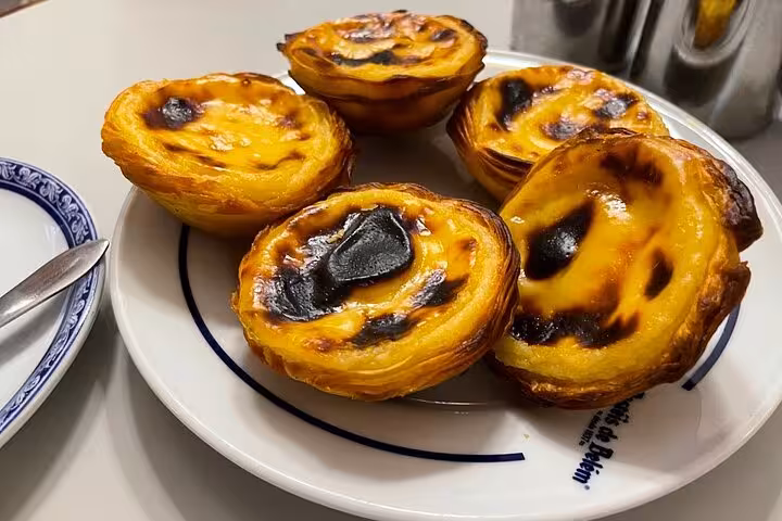Fresh pastéis de Belém custard tarts on a plate, included on private Tuk Tuk tour in Belém Lisbon