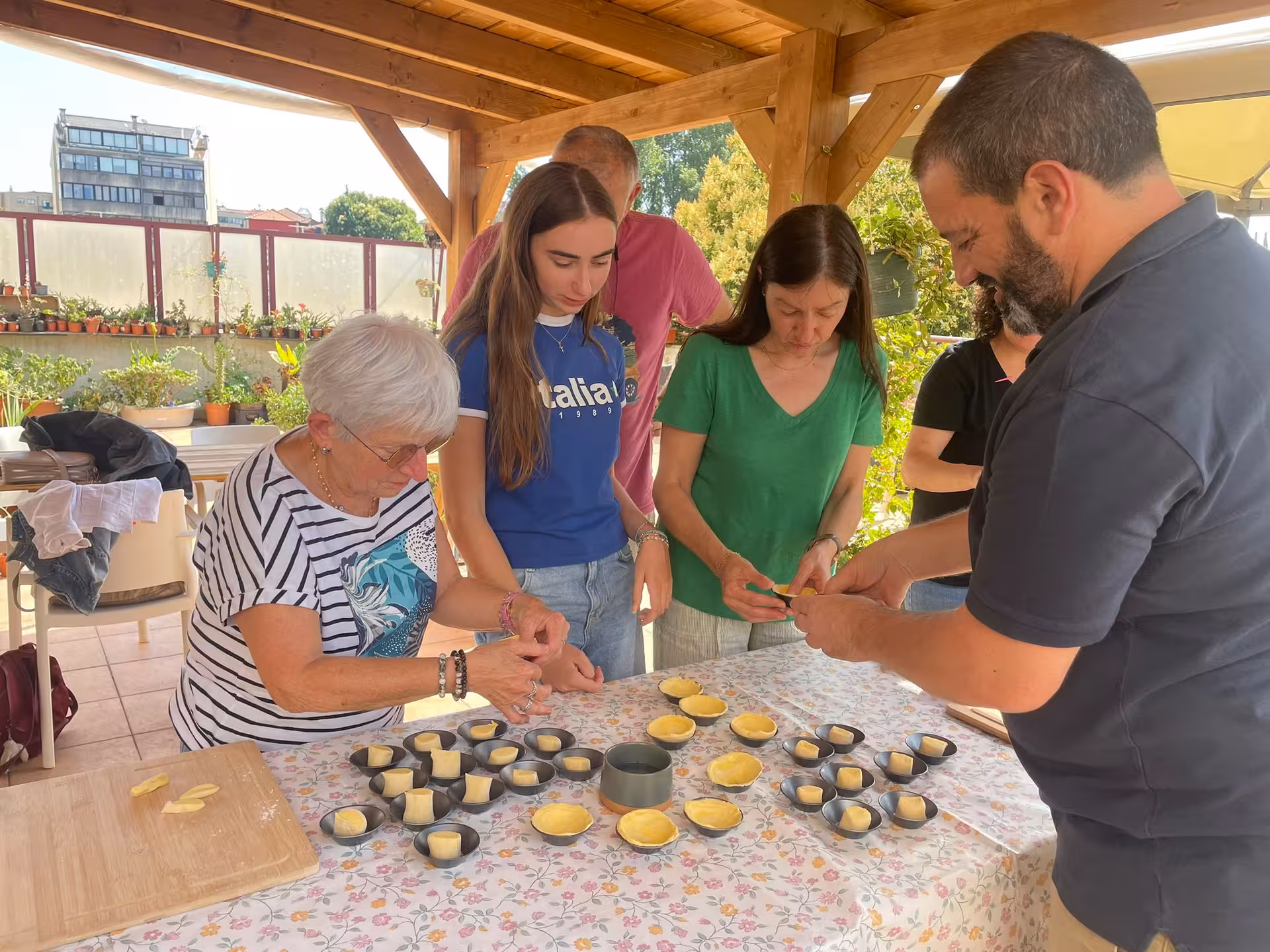 Participants preparing pastel de nata dough in a lively terrace cooking class with Isabel and Jorge.
