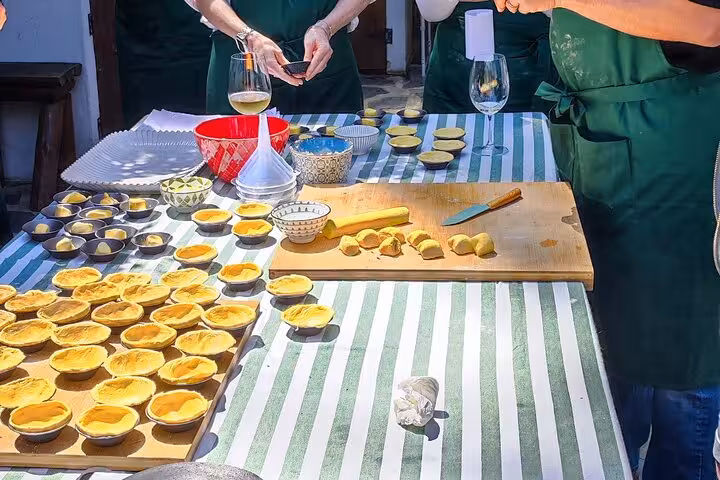 Outdoor pastry workshop with green aprons, showcasing the preparation of Pastel de Nata on a sunlit terrace.