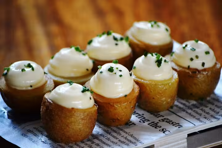 Indulge in gourmet patatas bravas topped with aioli, a classic dish on the Gràcia Catalan Food Tour in Barcelona.