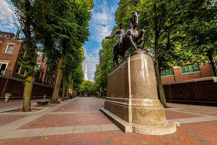 Paul Revere statue on brick mall lined with tall trees in Boston's North End neighborhood