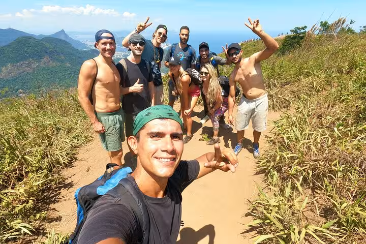 Energetic hikers pose on the vibrant Pedra da Gávea trail, capturing the excitement and scenic beauty of Rio's landscapes.
