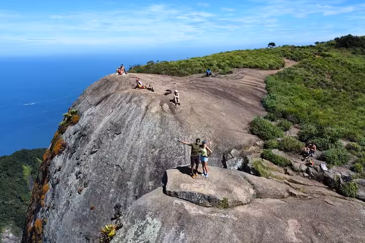 Visitors take in panoramic ocean views atop Pedra da Gávea, a stunning Rio de Janeiro hiking destination.