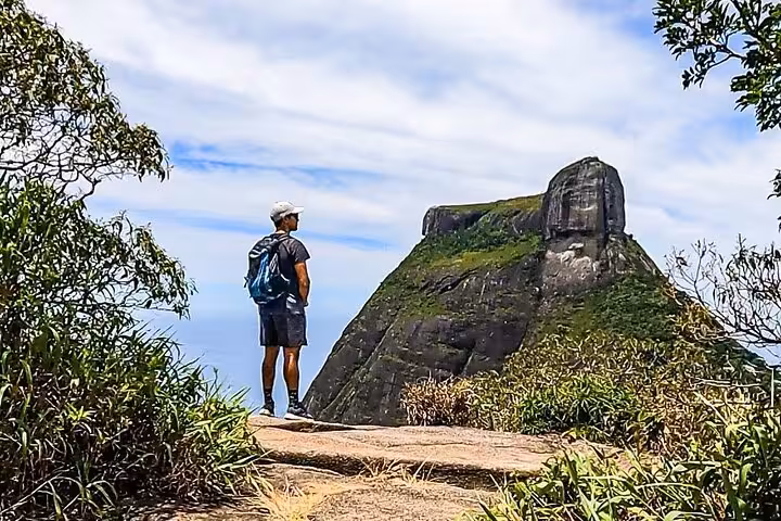 Man admiring the breathtaking view of Pedra da Gávea from a vantage point in Tijuca Forest, surrounded by nature.