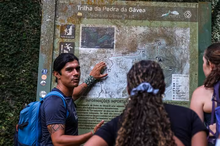 Tour guide explaining the Pedra da Gávea trail map to hikers, ensuring a safe and informative adventure.
