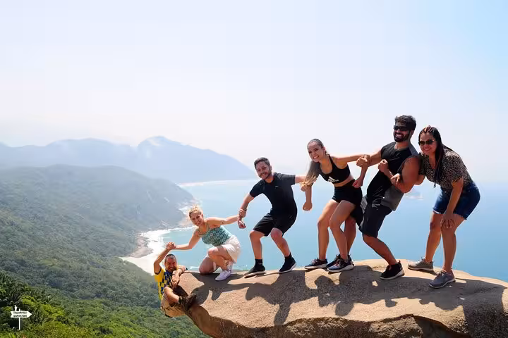 Group of friends posing on Pedra do Telégrafo rock, capturing memorable moments with scenic coastal backdrop.