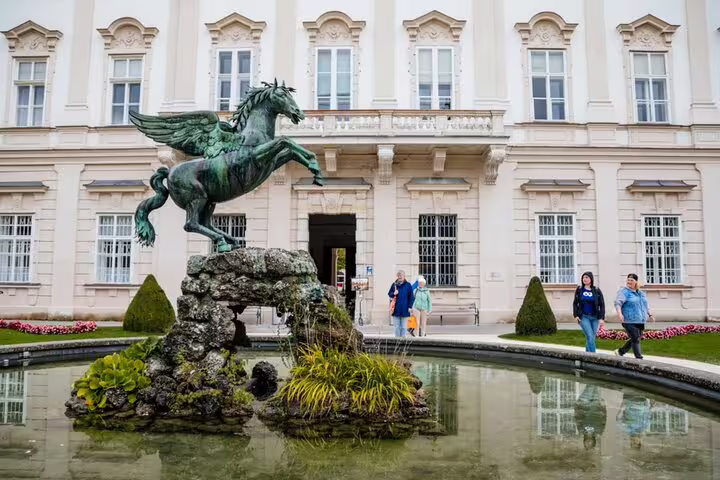 Pegasus fountain statue at Mirabell Palace gardens in Salzburg with tourists walking nearby