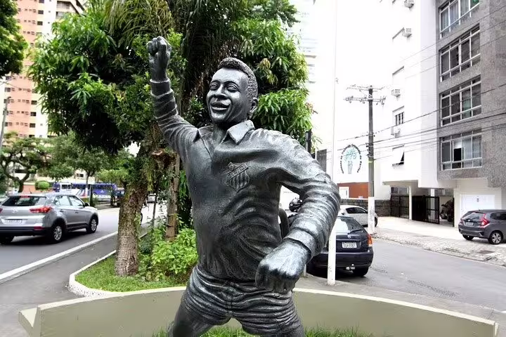 Pelé statue celebrates in a dynamic pose on a bustling street in Santos, Brazil.