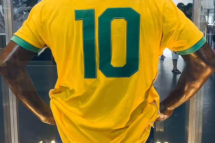 Back view of a Pelé statue wearing iconic yellow number 10 Brazil jersey in a museum display.