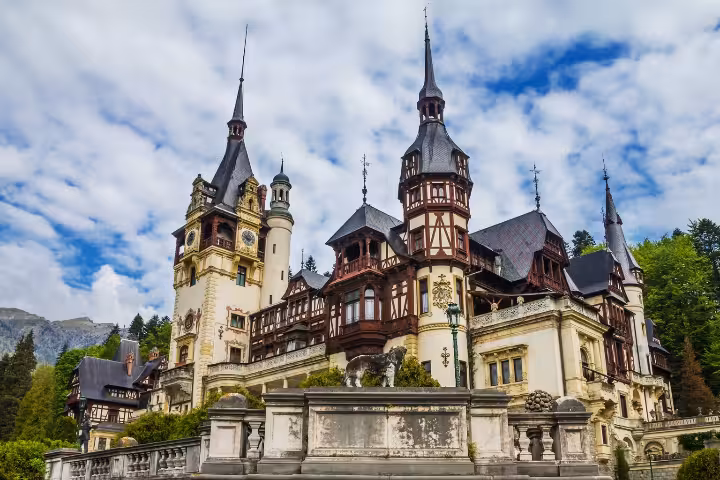 Majestic view of Peles Castle surrounded by lush greenery and mountains, a must-see destination on Romanian tours.