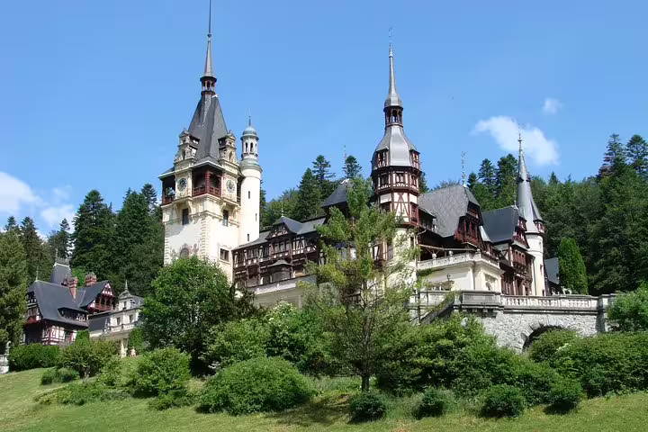 Peles Castle with ornate towers and half-timbered facades surrounded by pine forest in Sinaia, Romania