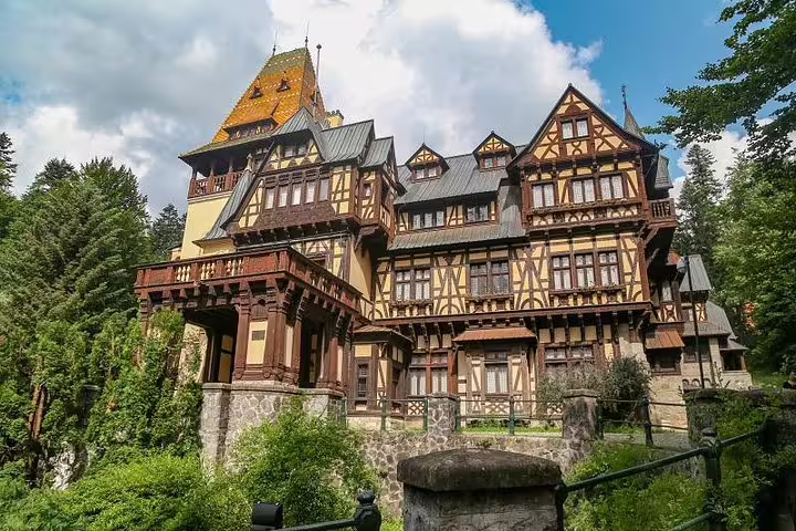 Peles Castle Tudor Revival architecture surrounded by forest trees in Sinaia Romania