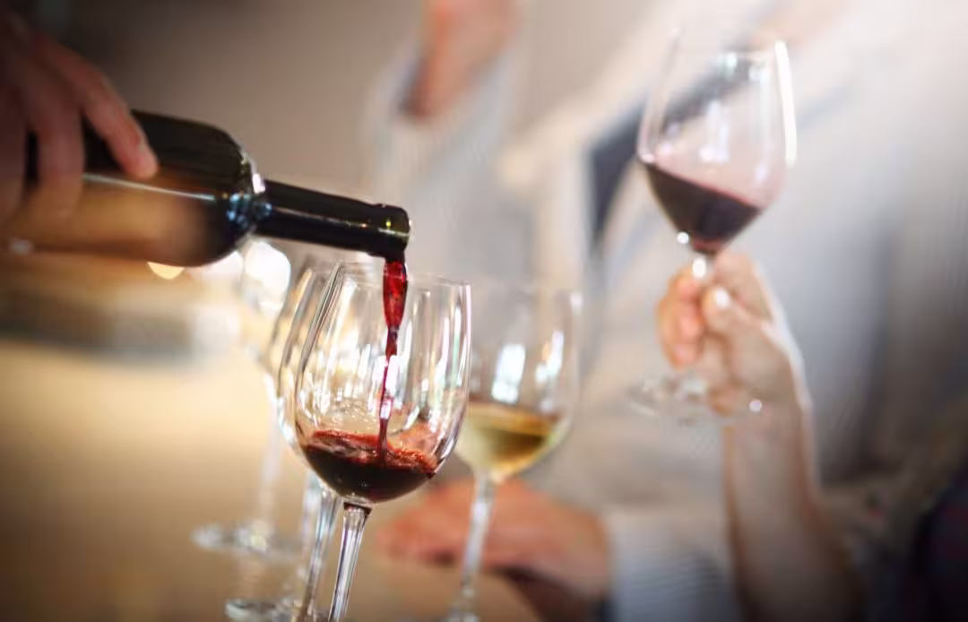 Pouring red wine into glasses during a Peloponnese day trip with lunch, showcasing local flavors and award-winning experiences.