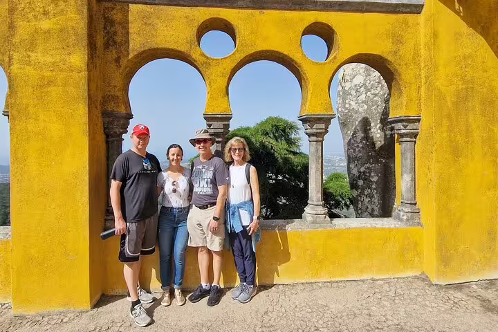 Tourists enjoying the vibrant arches of Pena Palace during a Sintra, Roca, and Cascais full-day private tour.