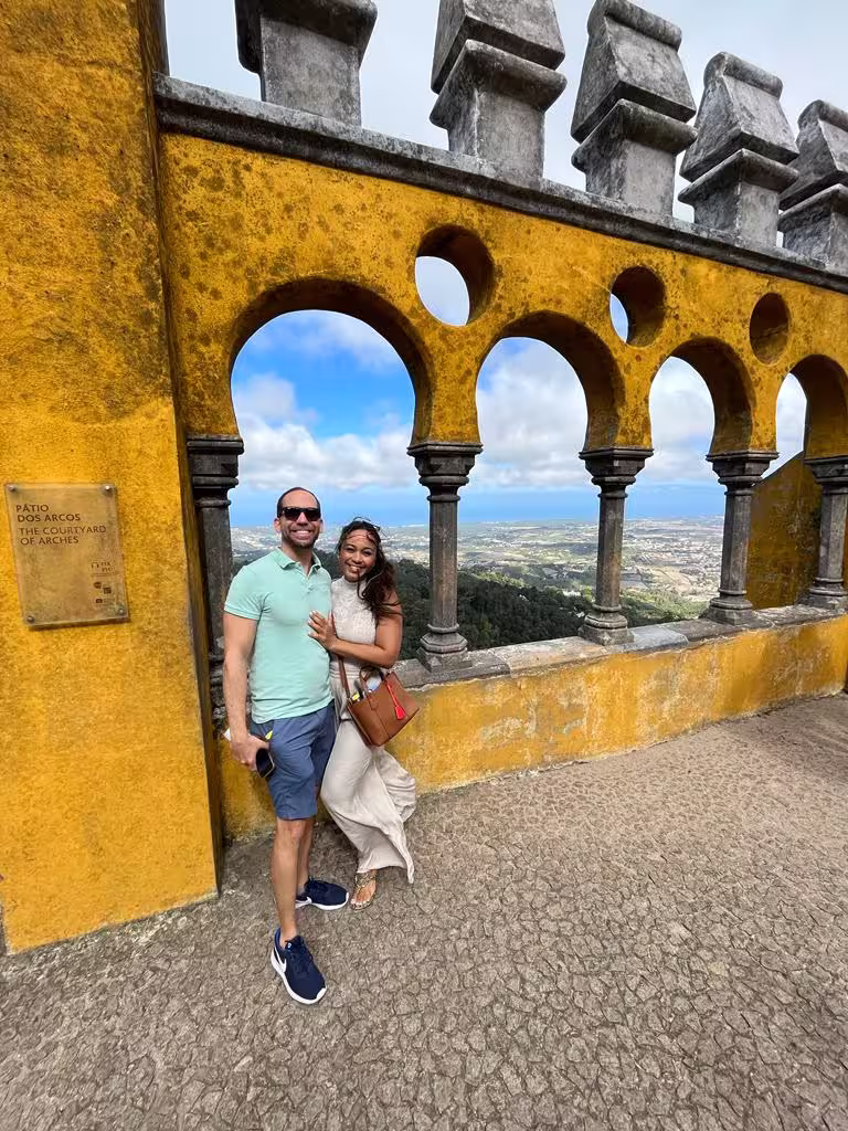 Tourists admire breathtaking views through arches at Pena Palace, Sintra, capturing its historic allure and scenic beauty.