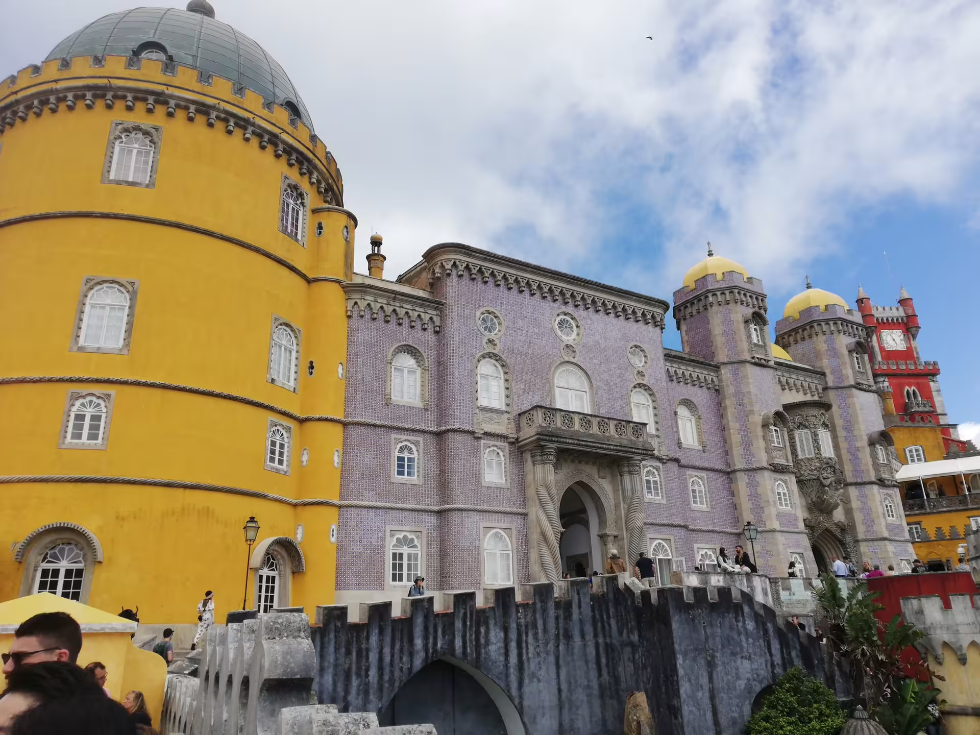The colorful towers of Pena Palace stand majestically under a bright sky on the Sintra & Cabo da Roca tour.