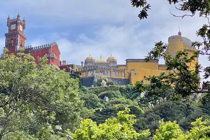 Majestic view of the colorful Pena Palace nestled in the lush greenery of Sintra, ideal for a Jeep tour visit.