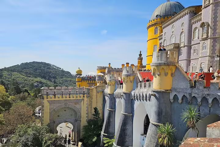 Vibrant view of Pena Palace in Sintra during a full-day tour from Lisbon, showcasing its colorful architecture and lush surroundings.