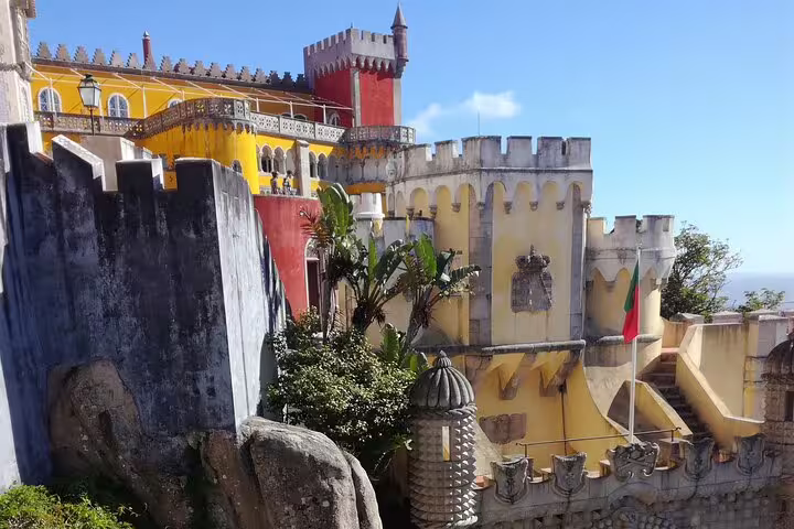 Vibrant view of Pena Palace's colorful facade in Sintra, Portugal, showcasing stunning architecture on a sunny day.