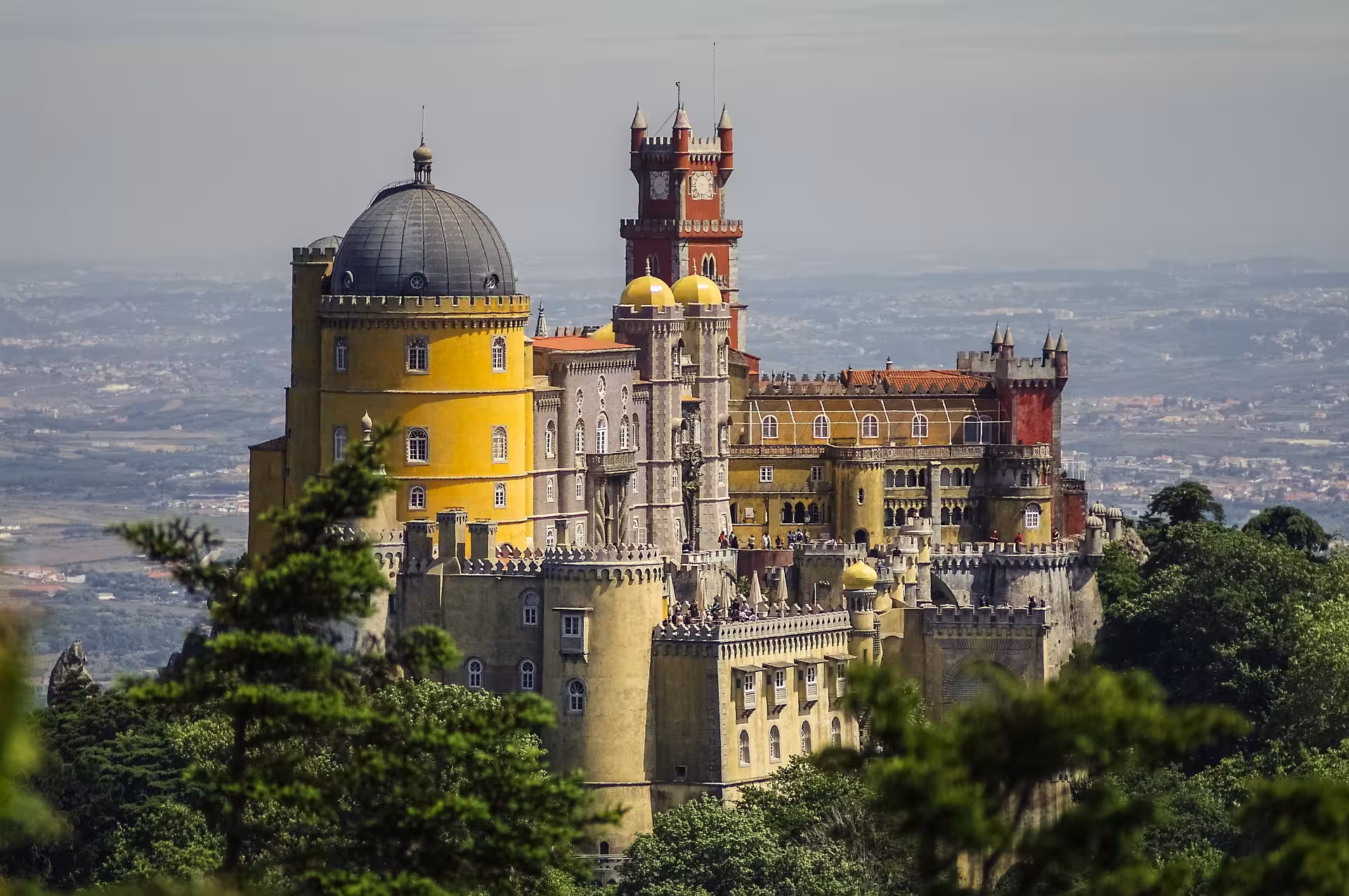Colorful Pena Palace perched on hilltop surrounded by lush forest on Sintra e-bike guided palace tour