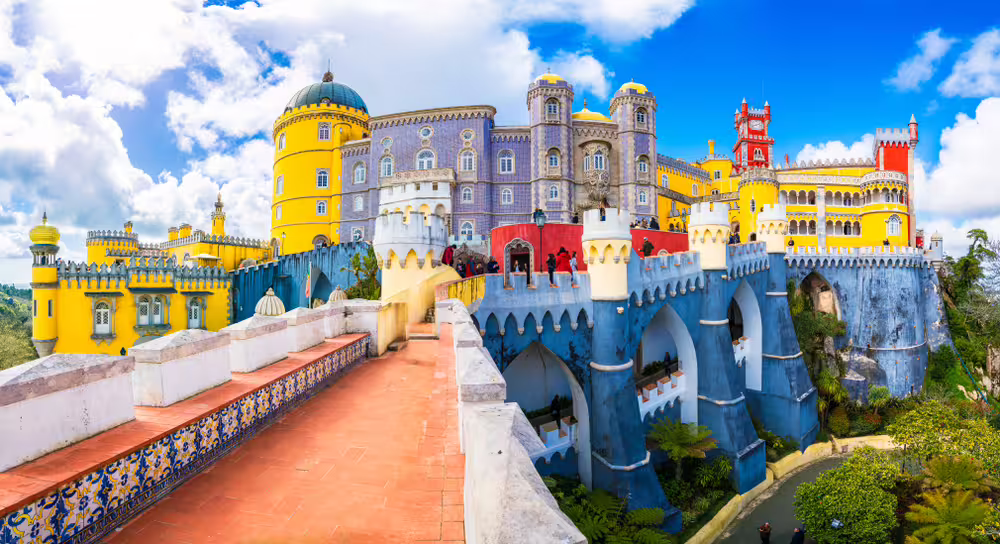 Vibrant view of Pena Palace's colorful architecture and lush gardens in Sintra, a highlight of the Lisboa tour.
