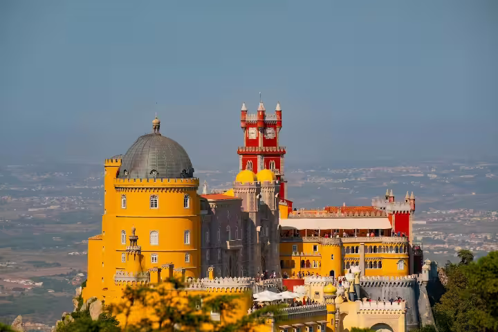 Vibrant view of Pena Palace in Sintra, Portugal, showcasing its colorful architecture on a half-day guided tour with tickets.