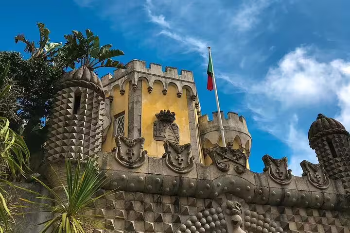 View of the ornate turrets and vibrant facade of Pena Palace under a clear blue sky on a Sintra full-day tour.