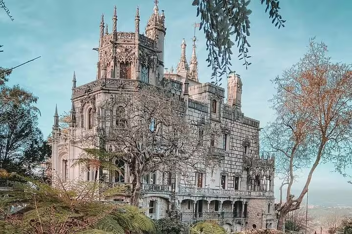 Majestic view of Pena Palace in Sintra, surrounded by lush greenery, featured in a half-day guided tour with tickets included.