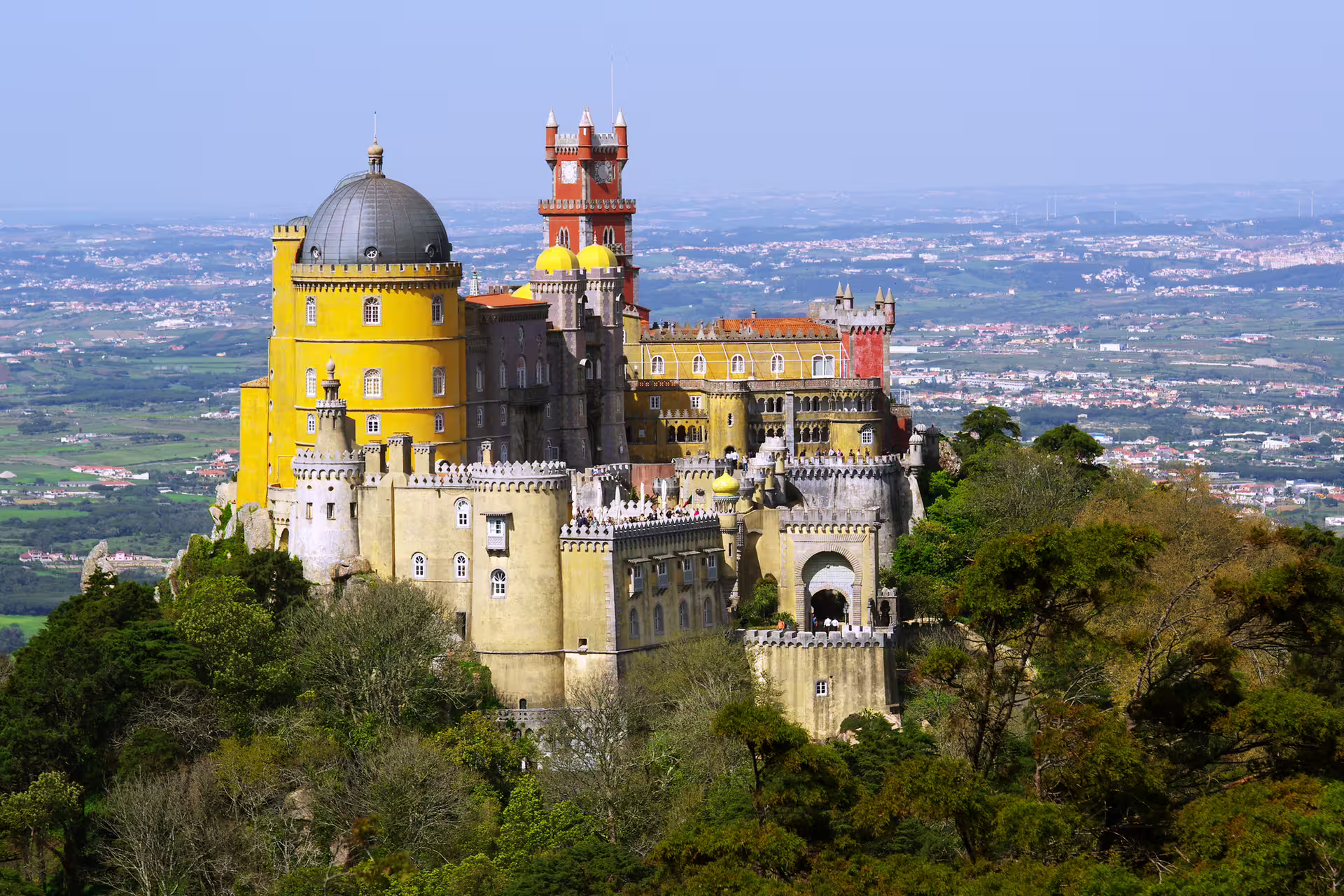 Vibrant view of Pena Palace in Sintra, Portugal, surrounded by lush greenery, part of Lisbon Sintra Estoril shore excursion.