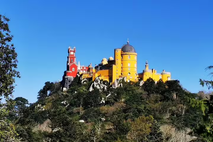 Vibrant Pena Palace in Sintra, Portugal, surrounded by lush greenery, part of a two-day private tour including Lisbon, Roca, and Cascais.