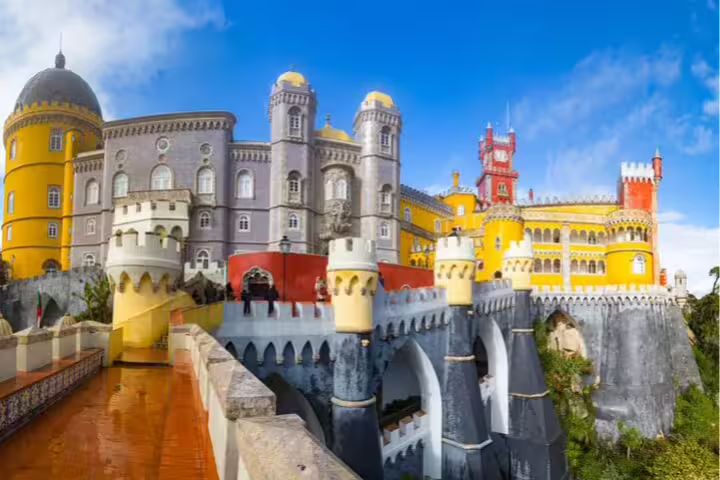 Vibrant facade of Pena Palace in Sintra, showcasing its unique architecture on a sunny day, featured in a full-day tour from Lisbon.