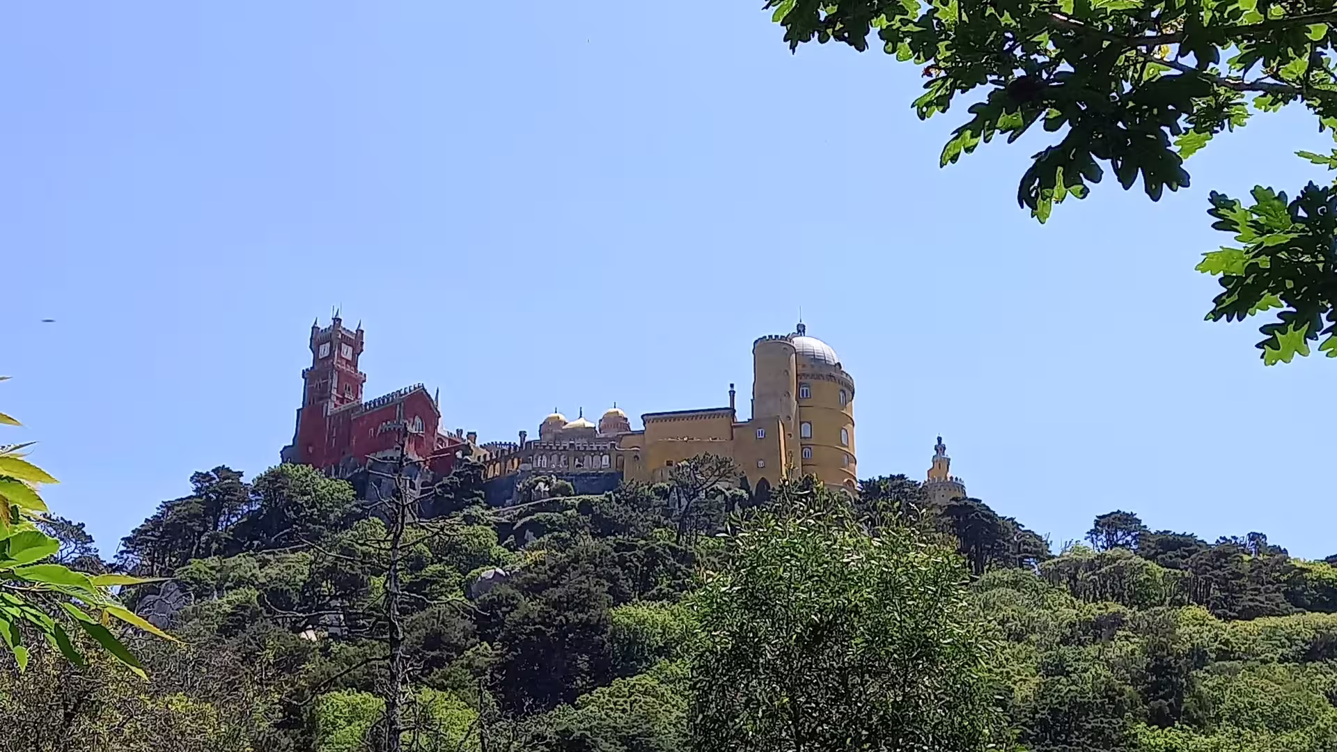 Scenic view of Pena Palace atop lush hills on the Belem Coast Road to Sintra tour from Lisbon.