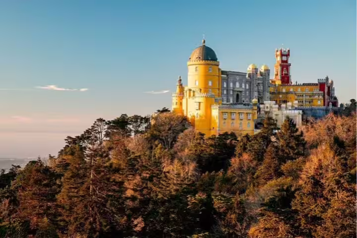 Vibrant Pena Palace perched atop Sintra Mountains surrounded by lush forests, ideal for guided tours and Moorish Castle visits.