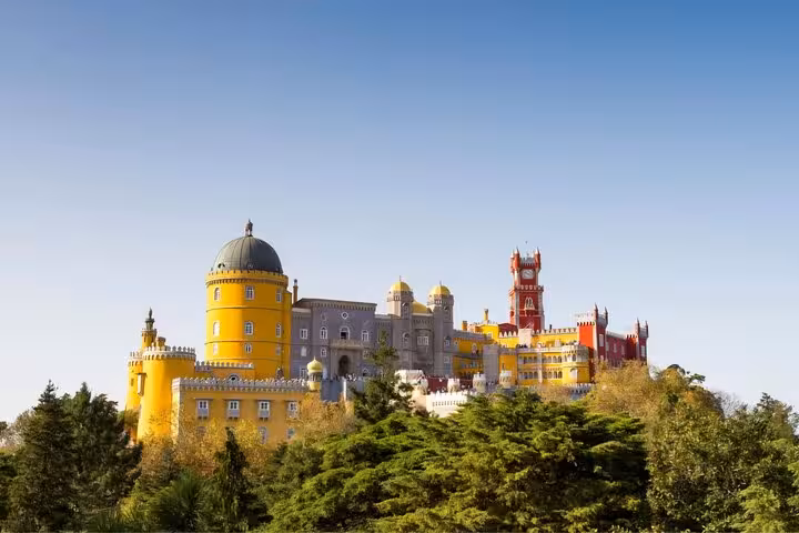 Panoramic view of the colorful and majestic Pena Palace nestled among lush greenery in Sintra, Portugal.