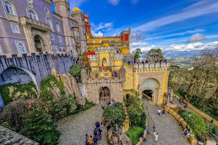 Vibrant view of Pena Palace in Sintra with tourists exploring, featured in a private tour from Lisbon with monument tickets.