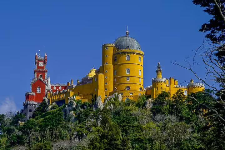 Vibrant Pena Palace in Sintra, Portugal, set against a clear sky, featured in our private tour with monument tickets from Lisbon.